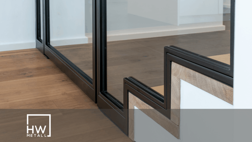 Detailansicht einer maßgefertigten Lofttür aus Stahl und Glas neben einer modernen Treppe im Industrial Design.