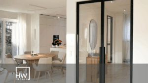 Moderner Wohnraum mit industriellem Flair, durch eine schwarze Loft-Schiebetür mit Glaseinsätzen vom angrenzenden Zimmer getrennt. Helle Wände, Holzfußboden und minimalistisches Interieur betonen den offenen, urbanen Stil.