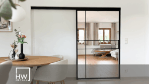 Moderne Lofttür aus schwarzem Stahl mit Glas, die als Raumteiler zwischen Wohnzimmer und Homeoffice dient. Viel Tageslicht fällt durch die Tür, wodurch beide Bereiche hell und offen wirken.